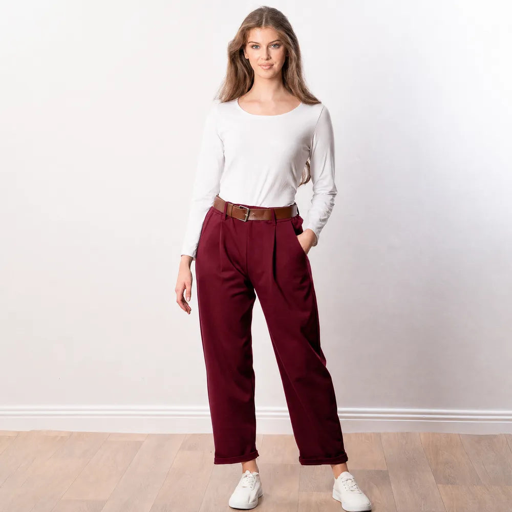 Arya Tapered Trousers in wine — front view, pleated tapered trousers styled with brown leather belt, white long-sleeve top and white trainers