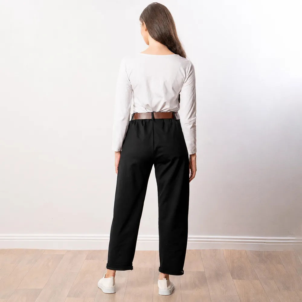 Black Arya tapered trousers back view with tan leather belt, white top and white trainers in a studio setting