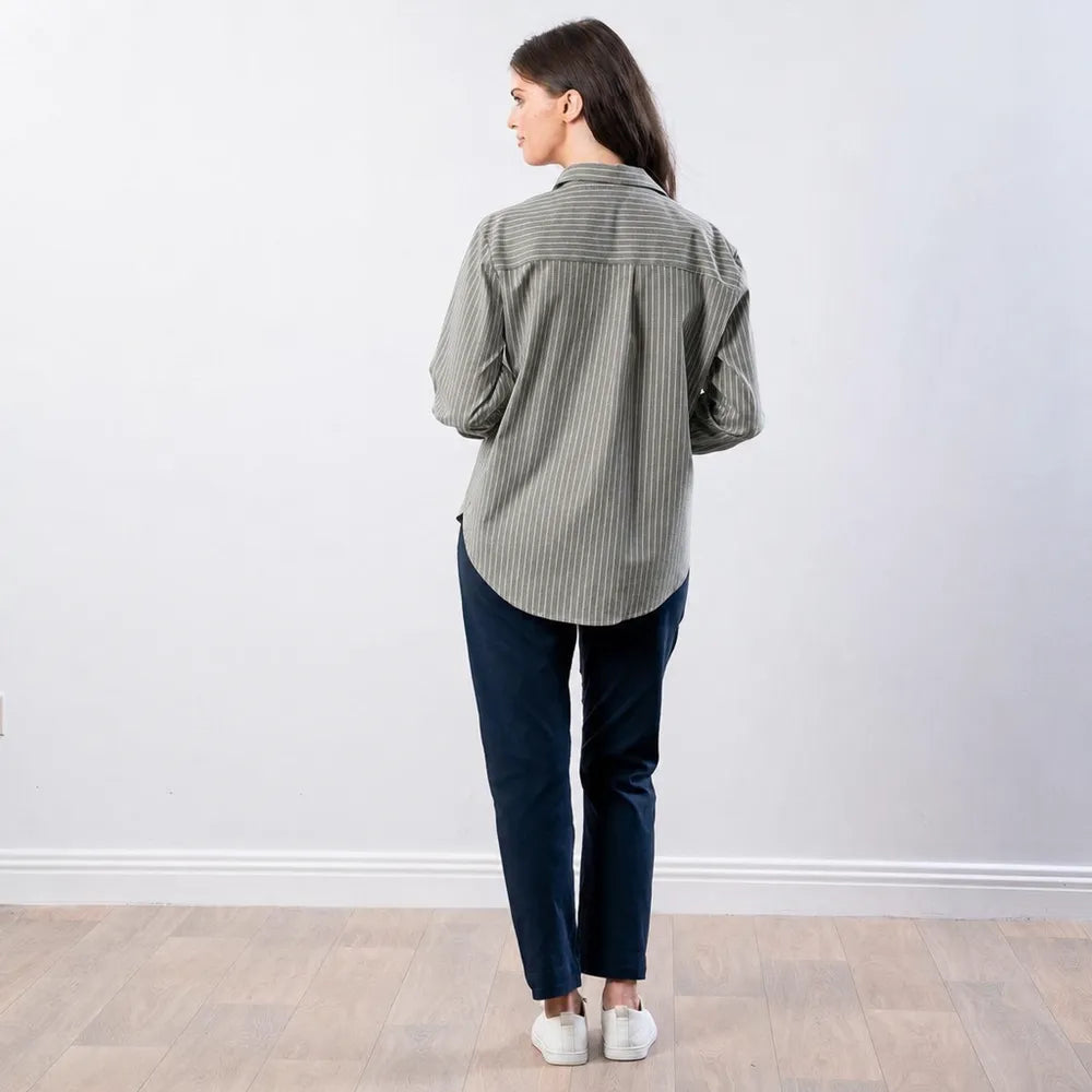 Back view of the Fallon Stripe Shirt in green with white pinstripes, showing the back yoke and curved hem, worn with navy trousers