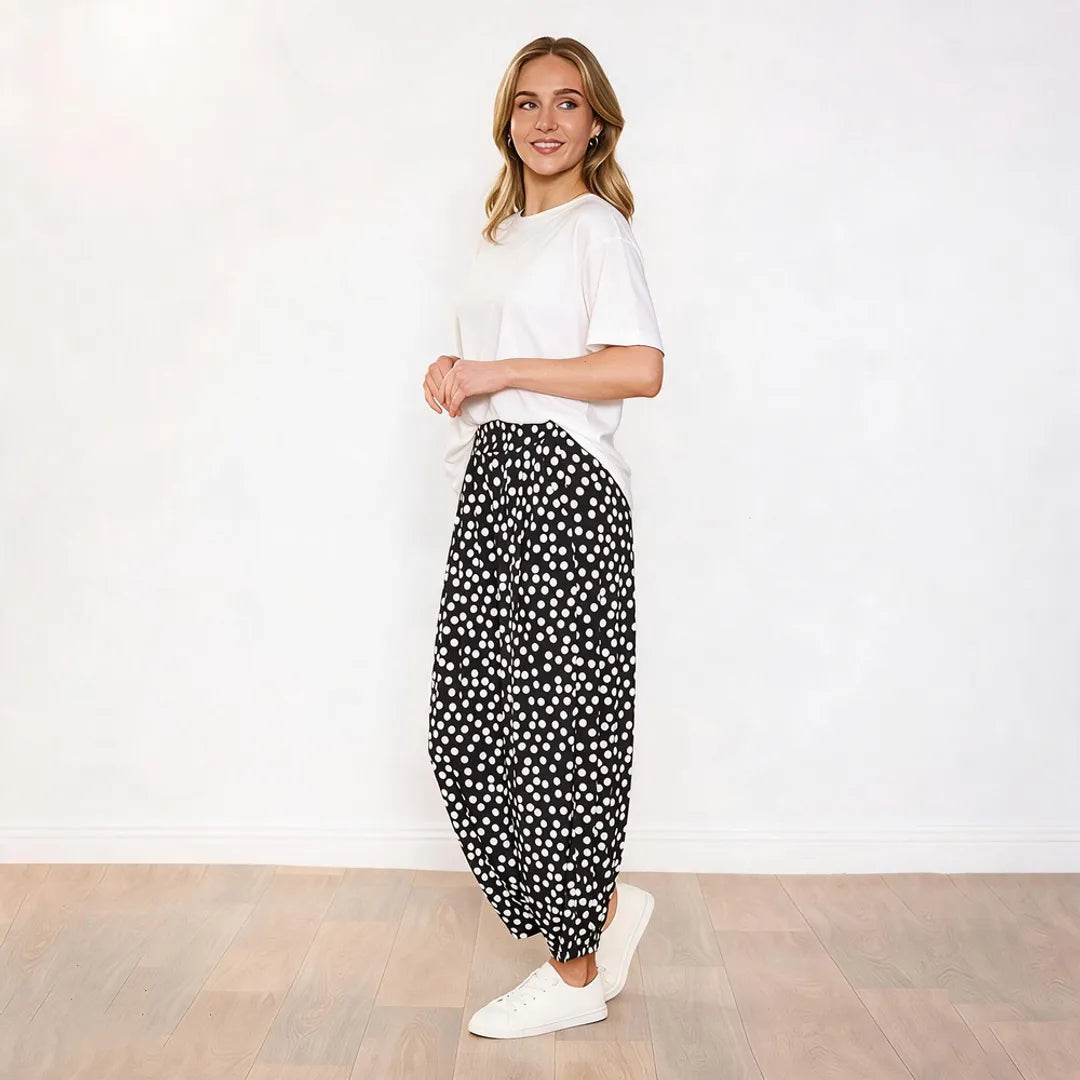 Side profile of Fraya black polka dot wide-leg trousers styled with a white tee and white trainers