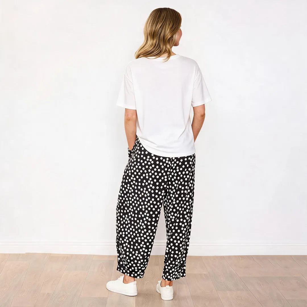 Back view of Fraya black polka dot wide-leg trousers with white tee and white trainers